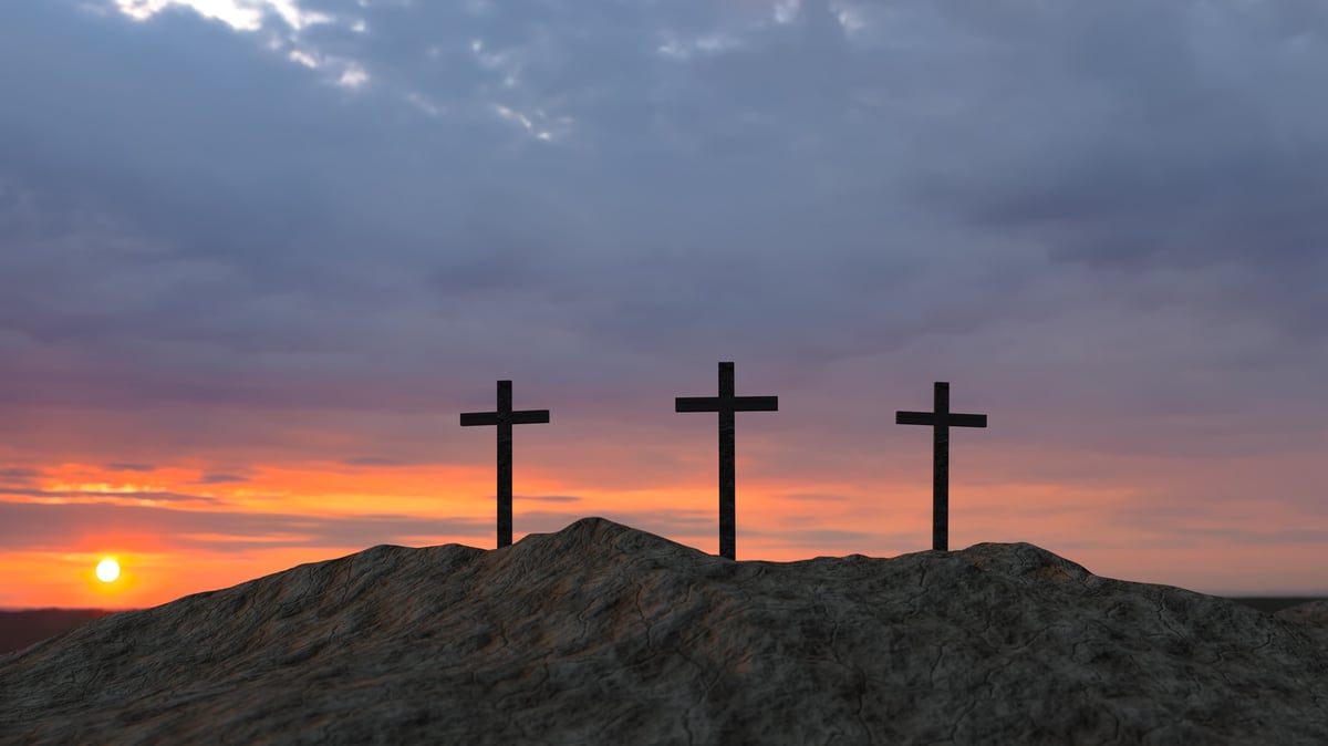Three crosses on a hill at sunset