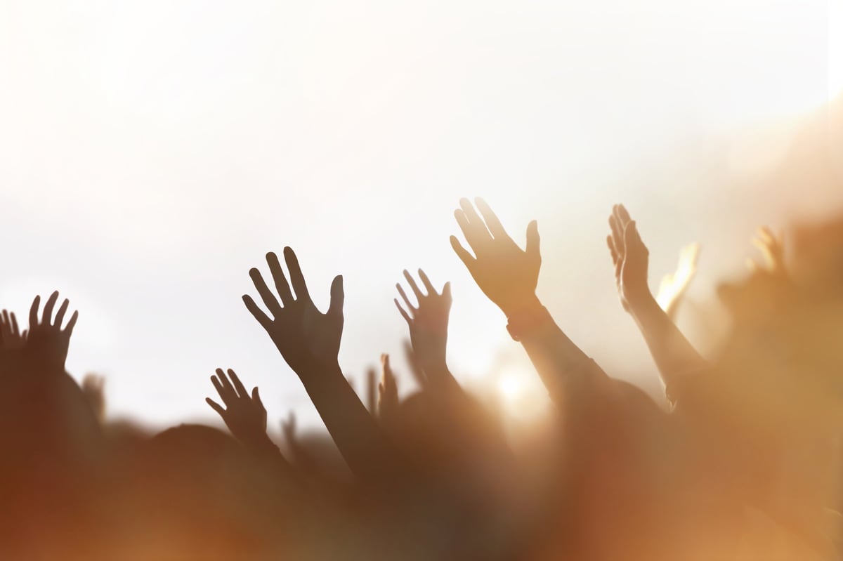 People raising hands in passionate worship and prayer, golden light illuminating a church congregation filled with hope and the Holy Spirit
